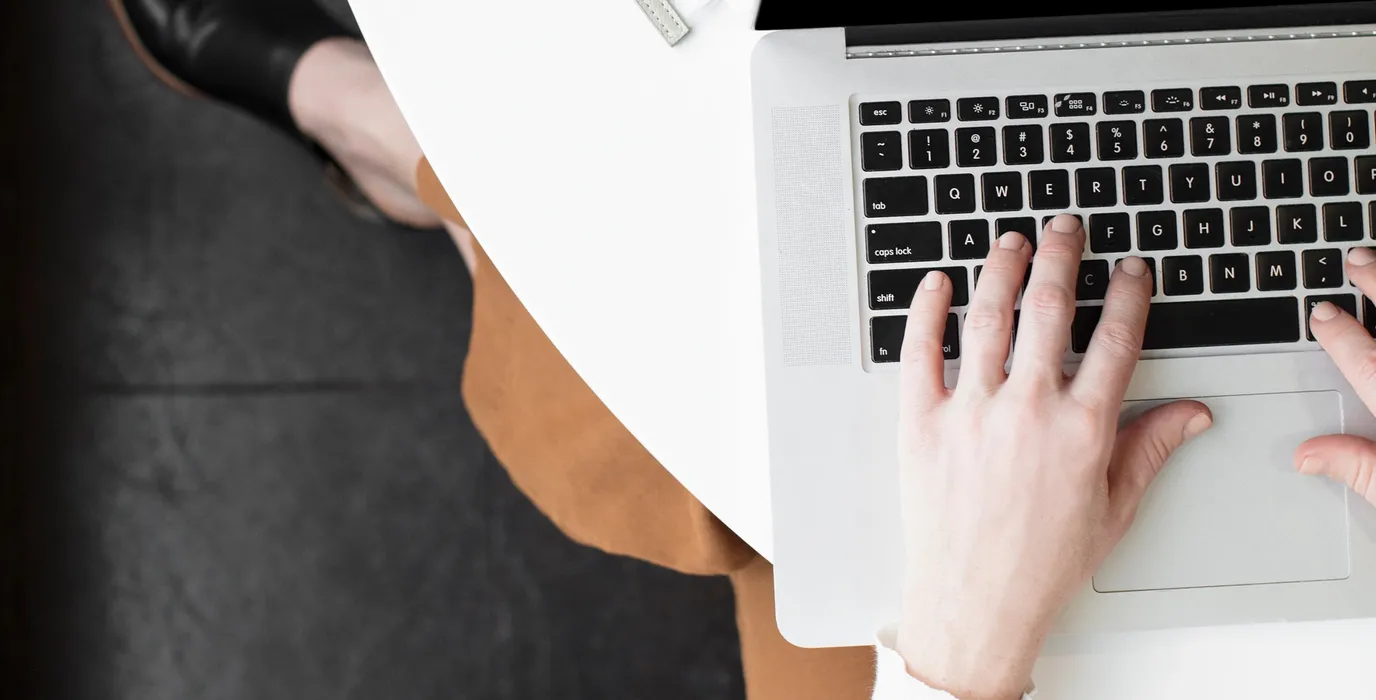 woman sitting at a desk while typing on her keyboard