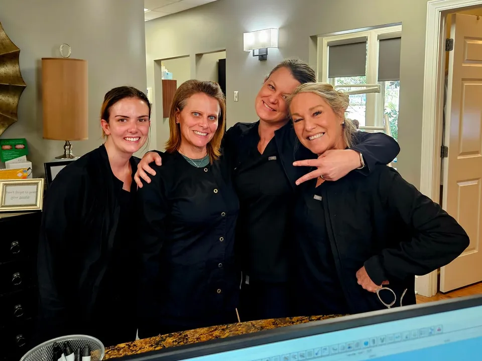 Four practice team members in dark scrubs posing together at a front desk