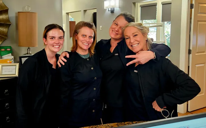 Four practice team members in dark scrubs posing together at a front desk