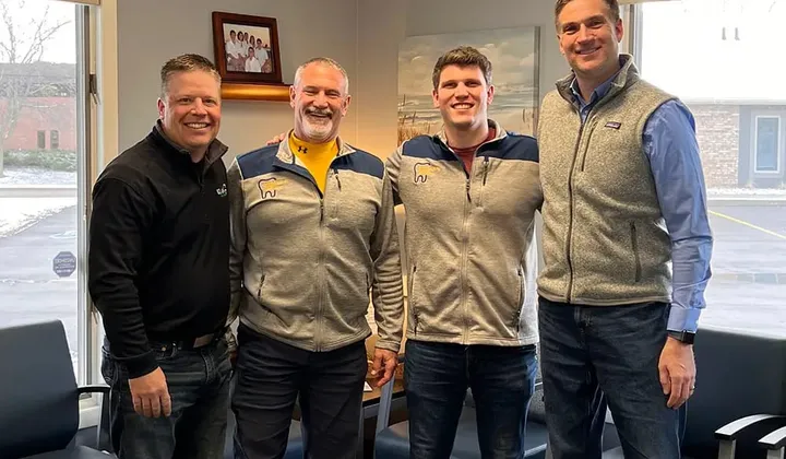Peter and Rick, father and son, standing with two men in a practice waiting room