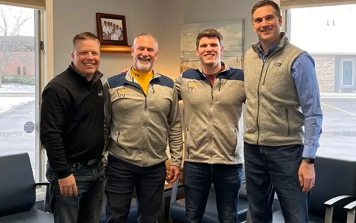 Peter and Rick, father and son, standing with two men in a practice waiting room