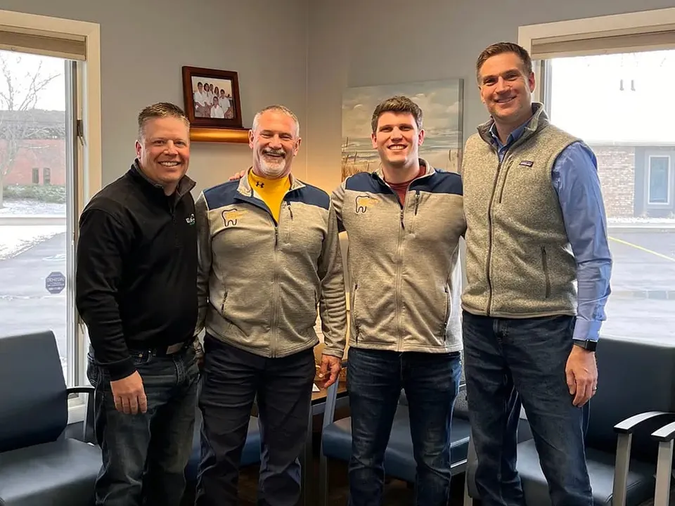 Peter and Rick, father and son, standing with two men in a practice waiting room