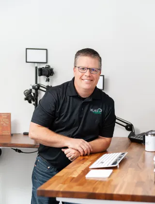 Phil Cole leaning on a standing desk and smiling
