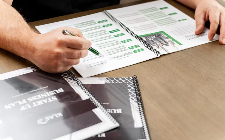 Hands completing a KLAS practice worksheet with a green pen