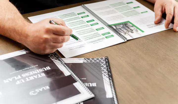 Hands completing a KLAS practice worksheet with a green pen