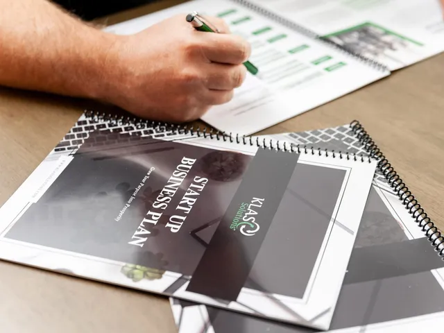 KLAS Solutions startup business plan workbooks stacked on a desk