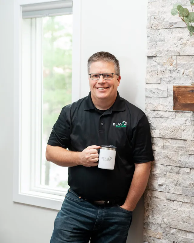 Phil Cole smiling with a KLAS Solutions mug