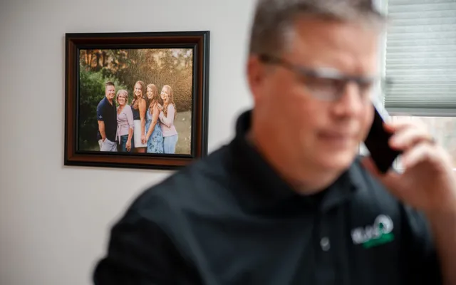 Phil Cole on a phone call with a framed family photo behind him