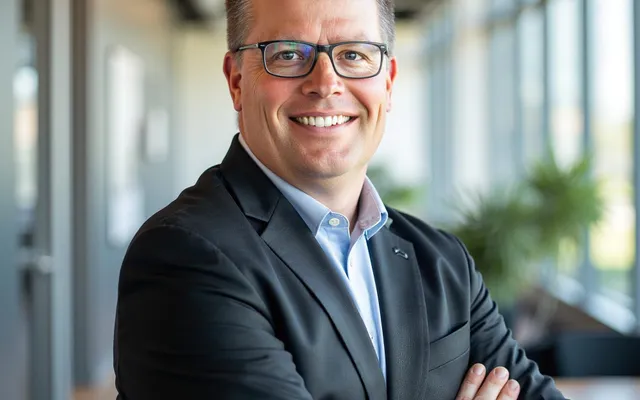 Phil Cole, founder of KLAS Solutions, smiling with arms crossed in a bright office